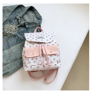 Close-up of white floral backpack with pink pocket details and fashion label