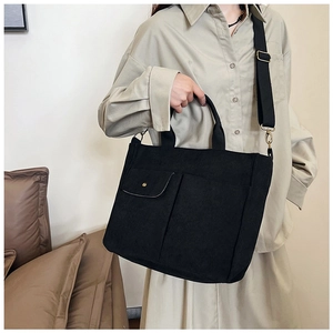 Détail d'un sac cabas noir en nylon avec bandoulière réglable et poches utilitaires
