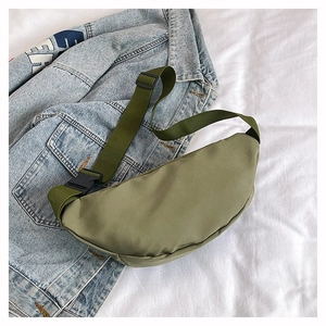 Détail d'un sac banane croissant en nylon vert armée sur une veste en jean bleue