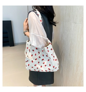 Vue latérale du sac fourre-tout en velours blanc avec imprimé fraises porté par un mannequin