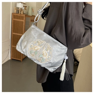 Detailed close-up of embroidered floral silk bag with metallic strap and elegant tassel