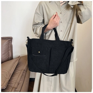 Détail d'un grand sac cabas en toile noire avec poches avant et bandoulière amovible