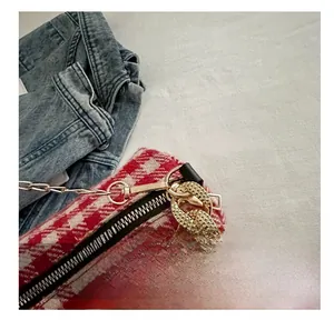 Détail du sac en tweed rouge et blanc avec ferrures dorées et crochet métallique sculpté