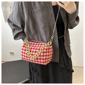 Détail du sac cylindre à carreaux rouges et blancs avec bandoulière en chaîne dorée