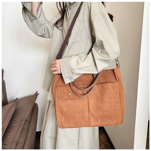 Détail d'un grand sac cabas en velours côtelé marron avec poche frontale et bandoulière