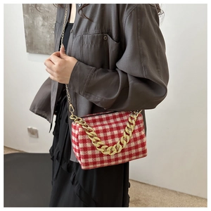 Détail du sac bandoulière à carreaux rouge et crème avec grosse chaîne dorée chic