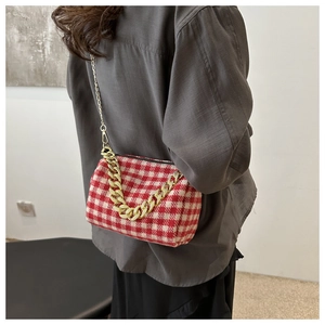 Détail macro du sac bandoulière en tweed à carreaux avec chaîne dorée et bandoulière fine