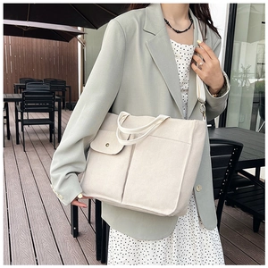 Photo en extérieur d'un sac cabas en toile blanc cassé avec poches à pression et bandoulière