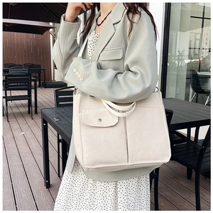 Détail du sac cabas en toile crème avec poche frontale et bouton pression métallique