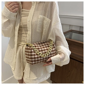 Détail du sac polochon à carreaux avec chaîne dorée porté par un mannequin