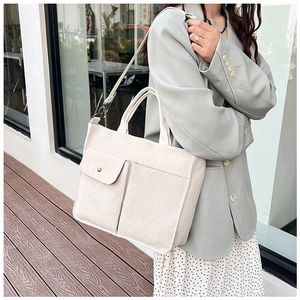 Détail du sac fourre-tout en toile beige avec grandes poches avant et bandoulière réglable
