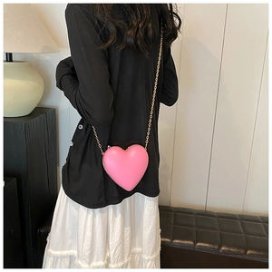 Sac bandoulière chic rose en forme de cœur avec chaîne dorée élégante porté par un mannequin