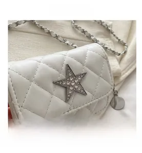 Macro shot of white quilted leather bag with rhinestone star and silver chain detail
