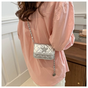 Detail of silver quilted chain bag with a sparkling star accent worn on pink shirt