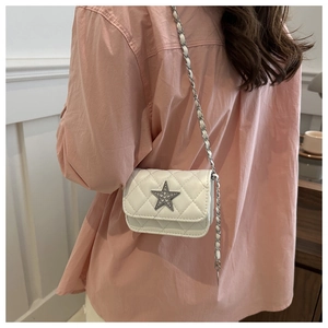 Macro detail of white quilted crossbody bag with rhinestone star and silver chain