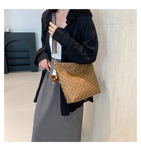 Brown tote bag with geometric patterns and colorful woven strap shown on model