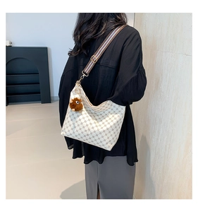 Detail of cream shoulder bag with floral print, striped webbing strap and lion charm