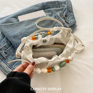 Detail view of white pleated cloud bag with colorful beads showing interior capacity