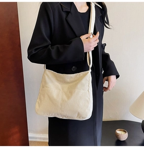 Close-up of a beige corduroy tote bag featuring soft ribbed texture and a wide shoulder strap