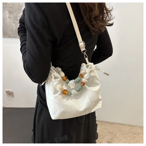 Detail of white bucket bag with colorful beads and marble texture on model back