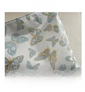 Macro detail of the butterfly golden embroidery and lace texture on the light blue handbag
