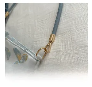 Close-up of golden metal hooks and blue floral jacquard fabric on a bucket bag