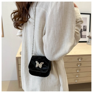 Detalle de minibolso bandolera negro con hebilla de mariposa plateada y cadena fina