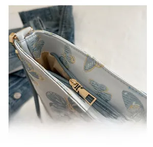 Close-up of golden zipper and butterfly embroidery on the light blue shoulder bag