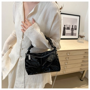 Detail of black pleated cloud handbag with shiny leather finish and silver chain strap