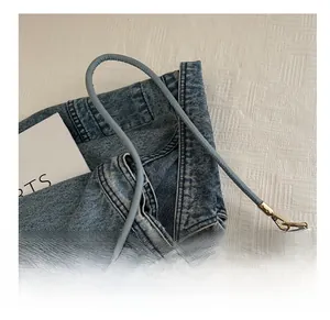 Detailed embroidery of blue and gold butterflies on a light blue bucket bag with leather strap