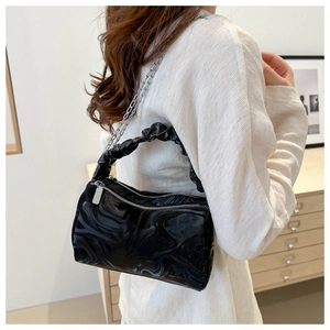 Detail of black glossy marble pattern handbag with silver chain and ruched handle