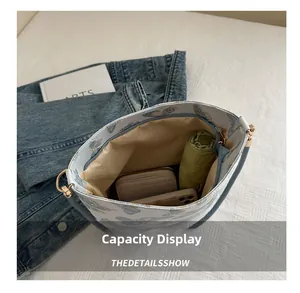 Detail view of large butterfly bucket bag interior holding a phone, wallet, and umbrella