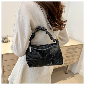 Detail of glossy black marble texture shoulder bag with pleated handle and silver chain
