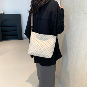 Chic cream tote bag with vintage monogram pattern and wide woven shoulder strap on model