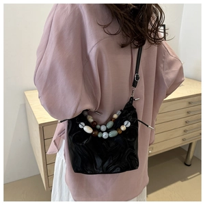 Detail of black marble textured pleated bucket bag with colorful beaded handle