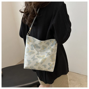 Detailed embroidery of gold and blue butterflies on a beige shoulder bucket bag