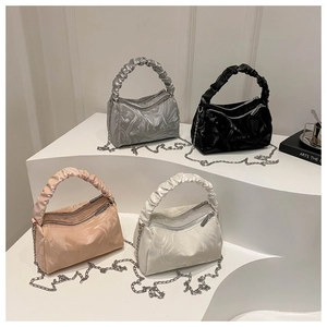 Minimalist ruched handle crossbody bags in silver, black, pink, and white on a pedestal