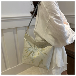 Detailed view of beige lace bucket bag with blue bamboo pattern and golden hardware strap