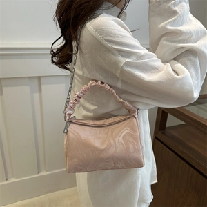 Pink marble pattern pleated handbag with silver chain strap shown on model's shoulder