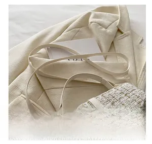 Detail of cream tweed crossbody bag with gold metallic weave and adjustable leather strap