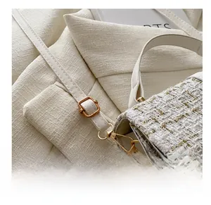 Macro detail of adjustable metal buckle and cream tweed texture on shoulder bag