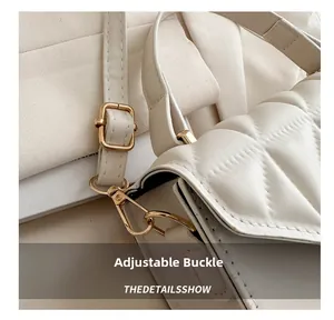 Close-up of adjustable golden buckle and stitched strap on a white quilted crossbody bag