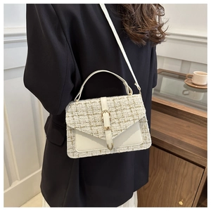 Detail of tweed and leather crossbody bag with belt buckle on a black blazer