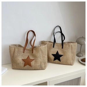 Detail view of woven straw tote bags with contrast leather star patches and handles