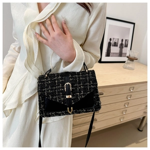 Close-up of black tweed crossbody bag featuring gold metal buckle and leather strap