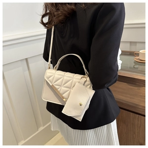 Detail of cream quilted crossbody bag with golden hardware and small hanging purse