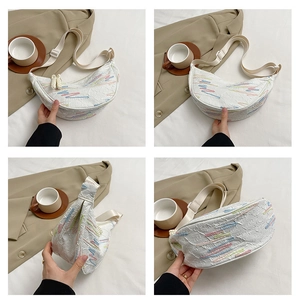 Macro view of cream crescent bag with colorful wavy textured embroidery and adjustable strap