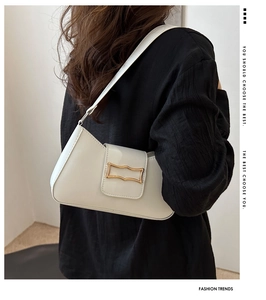 Detail view of a white PU leather underarm bag with gold metal buckle on a model