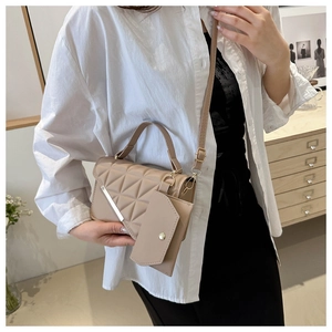 Detail of quilted beige crossbody bag featuring silver trim and an extra small pouch