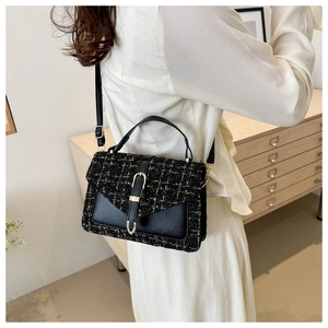 Dettaglio della borsa in tweed nero e pelle con finiture dorate e fibbia raffinata